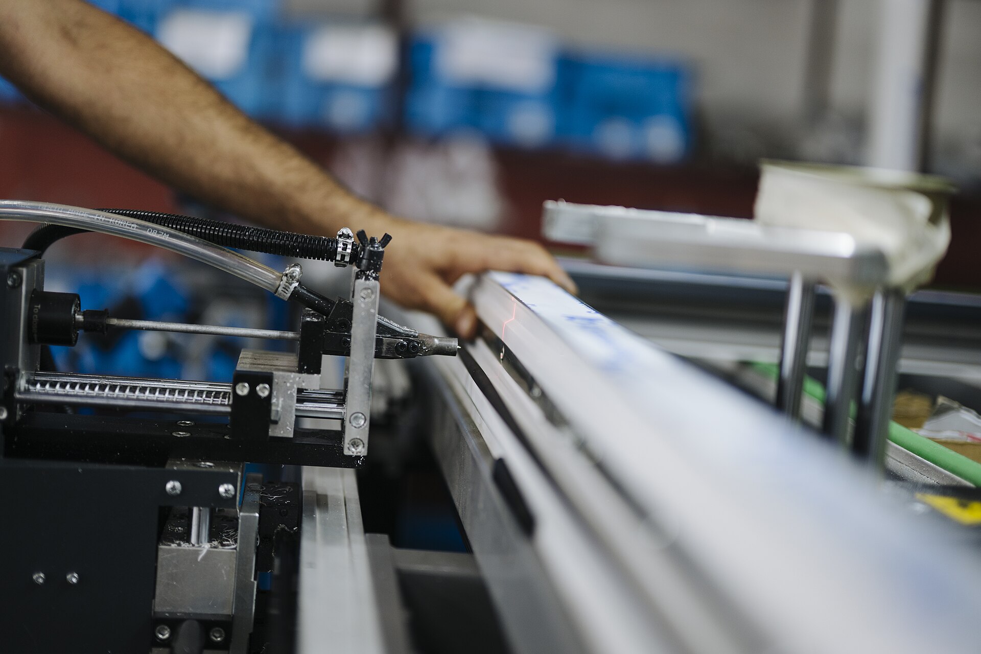 A worker’s hand beside machinery on a production line
